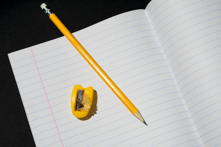 笔记本上的一个片段的照片放在一条线上，上面放着一支铅笔和卷笔刀上的刨花
