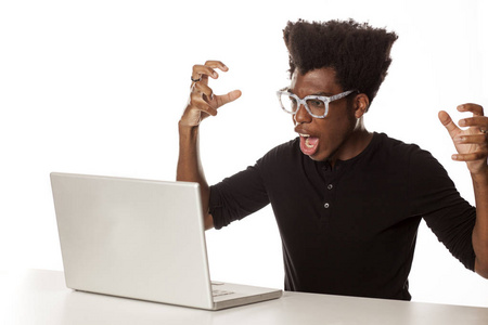 愤怒和紧张的年轻非裔美国人在办公桌上工作，白色背景上有笔记本电脑