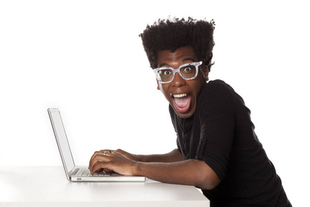 带着白色背景的笔记本电脑在办公桌前工作的美国黑人年轻人微笑着离开