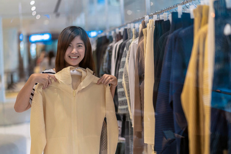 快乐的亚洲女人在百货商店里挑选衣服，在百货公司中心快乐地活动