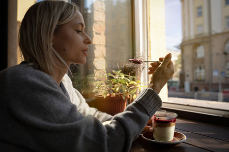 女人的手特写与一杯咖啡蛋糕, 太阳光线照耀通过在咖啡厅的窗口。手杯咖啡