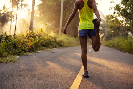 年轻的健身女性跑步者在晨跑之前伸展双腿