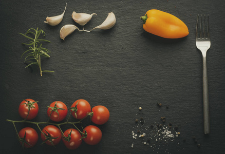 黑色石板板，西红柿，胡椒，大蒜，迷迭香叉和香料。 复制菜单的空间。 复古效果。