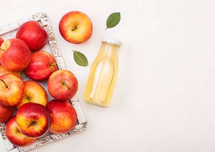 玻璃瓶新鲜有机苹果汁与红苹果在老式盒子上的木材背景。