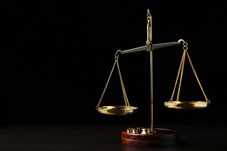 黑底木桌上的正义天平照片