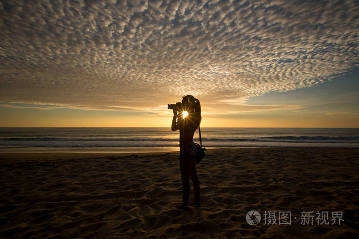 夕阳西下海岸年轻女摄影师的剪影