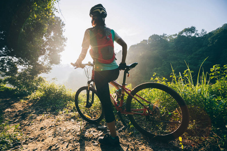 年轻女子骑自行车在夏季森林小径上骑着山地车