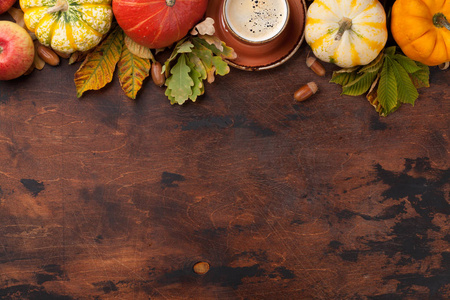 秋天的背景，南瓜，咖啡和五颜六色的叶子在木制背景。顶部视图与您的文本空间