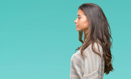 漂亮的阿拉伯女人穿着冬天的毛衣,在孤立的背景下,看着侧面放松的轮廓