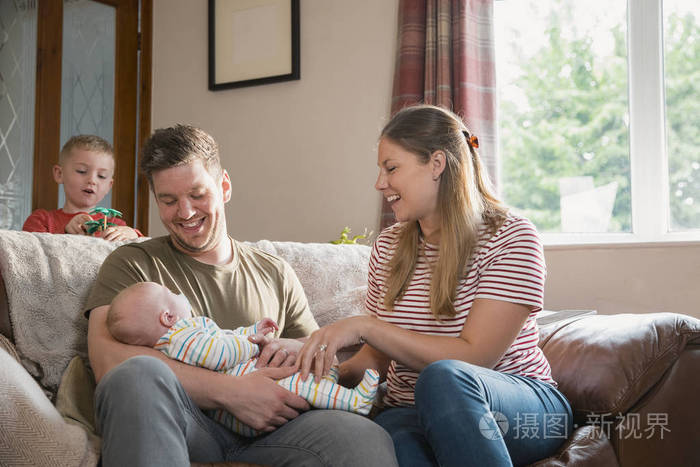 那个男人抱着孩子,他的妻子正试着微笑着和他一起笑.