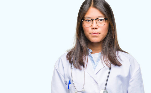 年轻的亚洲医生女性，在孤立的背景下，脸上有严重的表情。 简单自然地看着相机。