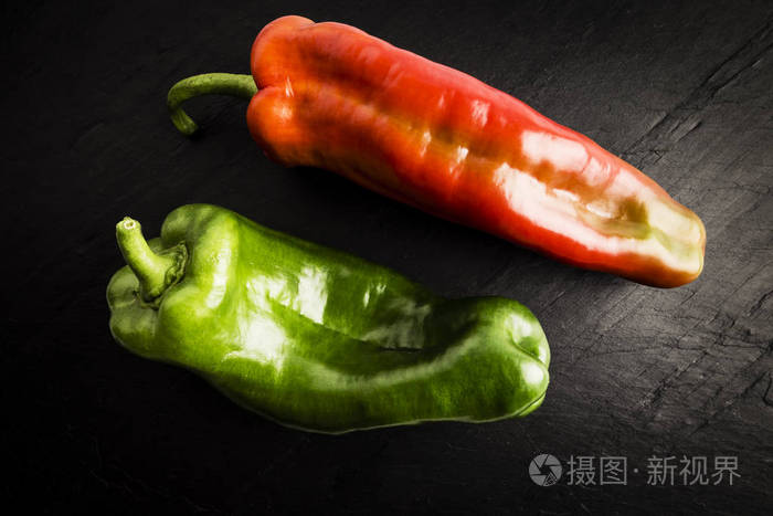 在黑色石板桌上放一个新鲜的青红椒