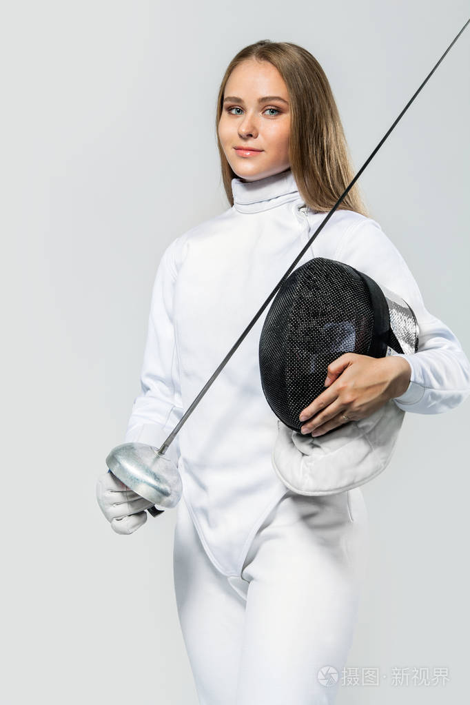 年轻的击剑运动员穿着击剑服装握着剑和面具在白色背景下隔离