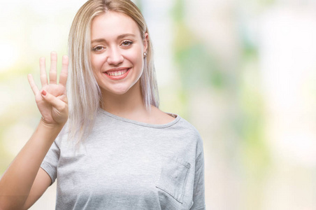 年轻的金发女子在孤立的背景显示和指着第四个手指，同时微笑自信和快乐。