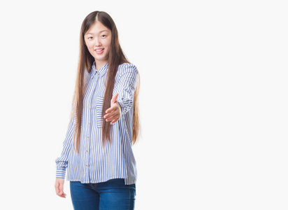 年轻的中国妇女在孤立的背景下微笑友好地提供握手作为问候和欢迎。 成功的生意。