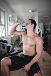 年轻有魅力的成年人在健身馆喝水。 室内运动训练。