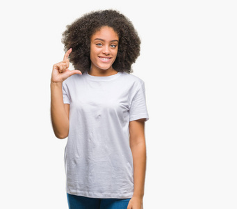 年轻的非洲美国妇女在孤立的背景上微笑和自信的手势与手做大小标志与手指，同时看和相机。 测量概念。