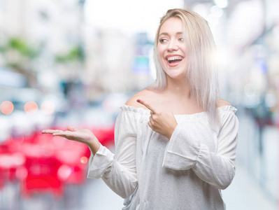 年轻的金发女人在孤立的背景下惊讶和微笑的相机，同时呈现手和手指。