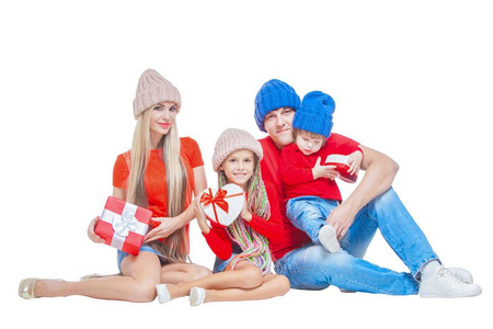 家庭在圣诞节。欢快的家庭在帽子看着相机和微笑, 而孤立的白色。礼品盒在手。肖像爱家庭特写