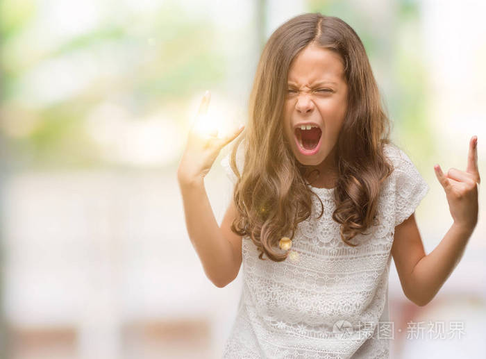 黑发西班牙女孩大声喊叫,疯狂的表情,做岩石符号与举手. 音乐明星.