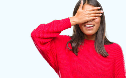 的亚洲女人穿着冬天的毛衣,在孤立的背景上微笑,笑着,用手捂着眼睛,为