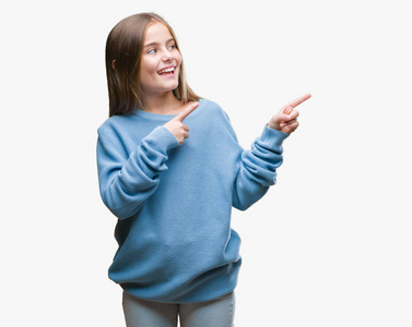 年轻漂亮的女孩穿着冬天的毛衣，在孤立的背景上微笑，看着相机，用两只手和手指指向一边。