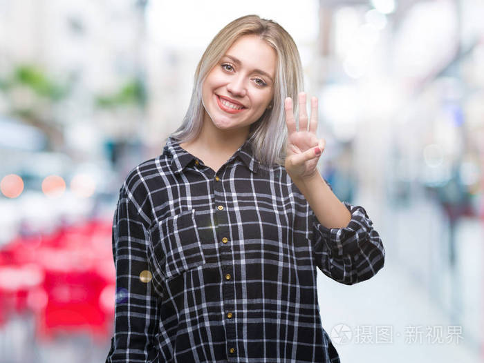 年轻的金发女子在孤立的背景显示和指着第三个手指，同时微笑自信和快乐。