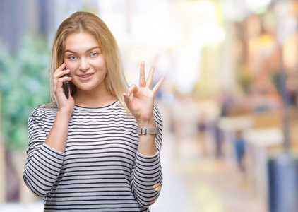 年轻的白种人女人在孤立的背景上显示智能手机屏幕，用手指做OK标志，优秀的符号。