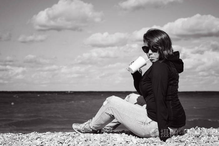 红发女人带着咖啡在海边放松