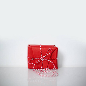 用红纸包裹的圣诞礼品盒，白色背景的三角绳