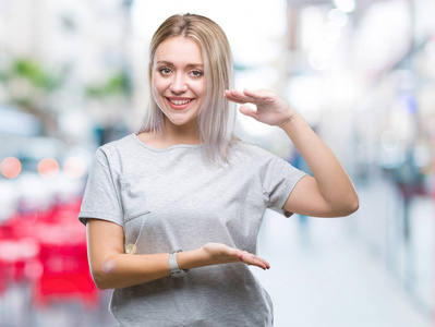 年轻的金发女人在孤立的背景上做手势，双手显示大尺寸的符号测量符号。 微笑着看着相机。 测量概念。