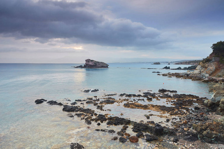 石头和岩石在最前沿，奶油冲浪，潮起潮落，在塞浦路斯的Polis海滩。 背景包含更多的海岸线和地平线上的特洛伊多斯山脉。