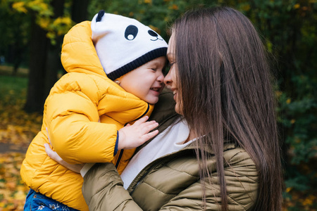 家庭户外快乐。 妈妈在秋天公园拥抱年幼的女儿。 特写肖像。