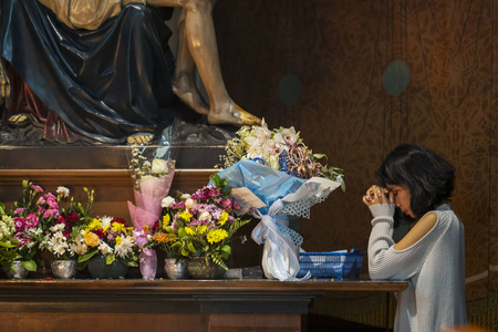 亚洲妇女在教堂祭坛旁祈祷时向上帝祈求宽恕的肖像照片