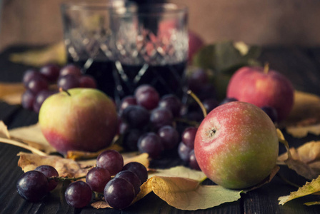 两个水晶杯，上面有红葡萄酒苹果葡萄和干叶
