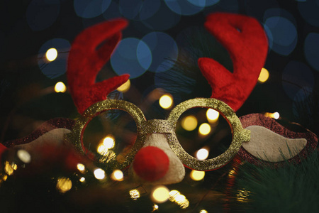冷杉树枝上的圣诞驯鹿眼镜。 美丽的灯光