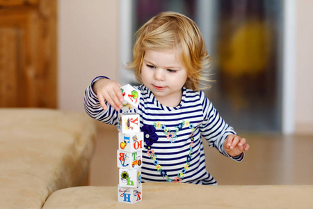 可爱的学步女孩在托儿所玩教育玩具。快乐健康的孩子在家里玩五颜六色的不同塑料块。可爱的婴儿学习创造和建设