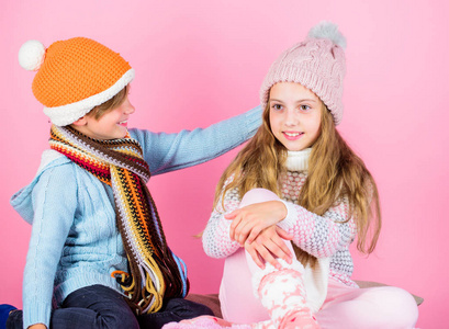 女孩和男孩穿针织冬季帽子。冬季时尚饰品和服装。儿童嬉戏的心情圣诞假期粉红色的背景。儿童针织冬季帽子。儿童冬季配件