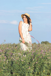 美丽的年轻女子穿着白裙在田野上，柔和的焦点背景