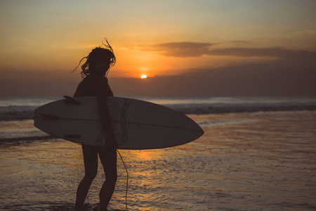 日落时分带冲浪板的女性剪影