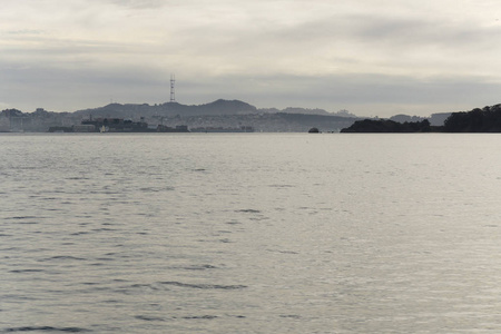从水上的一艘船上看到的旧金山海湾上空多云的日落。 城景和金门大桥