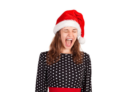 自信而调情的可爱女人穿着裙子，在镜头前高兴地大喊大叫，哭得很大。 情感女孩在圣诞老人圣诞帽隔离在白色背景。 假日概念。