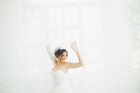 美丽的新娘穿着婚纱时有长时间充分的裙子，白色背景，跳舞和微笑
