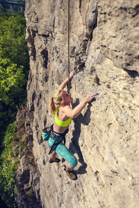 女孩爬上岩石。 女人在大自然中从事健身活动。 极限运动。 攀登路线。 为比赛做准备。 实现目标。 努力完成任务。 锻炼。