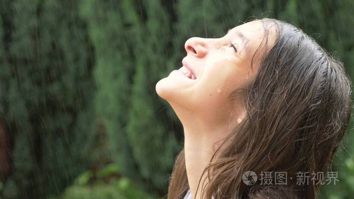 特写一个年轻女孩的肖像看雨在自然界与湿头发女孩在倾盆大雨中欢喜