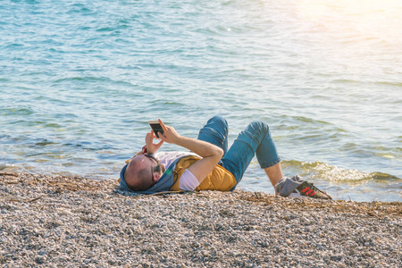 黑山共和国2017年5月5日躺在海滩上看电话的人