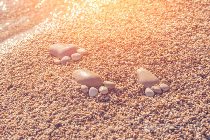 阳光下，沙滩上的鹅卵石构成的足迹