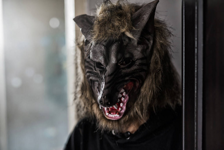 狼人杀背景男人带着狼面具和黑色礼服服装在黑暗的房间里,从窗户发出