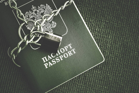 俄罗斯护照上覆盖着一条链子，在纺织背景上有一把金锁。 色调