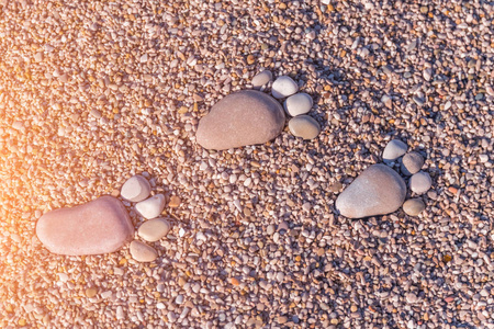 阳光下沙子上的石头留下的脚印
